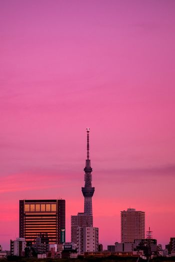Buildings in city against romantic sky at sunset