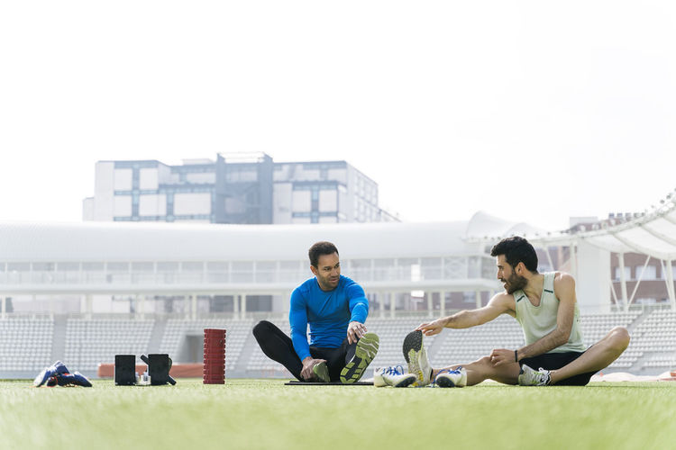 Friends sitting on mobile phone against sky
