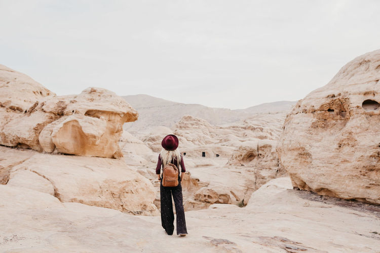 Rear view of woman walking on desert against sky