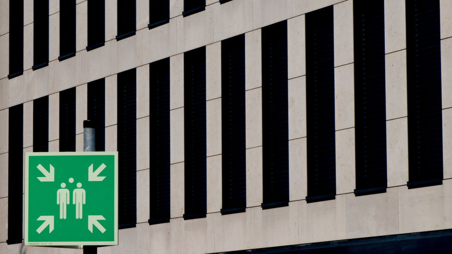Green information sign in front of wall of building