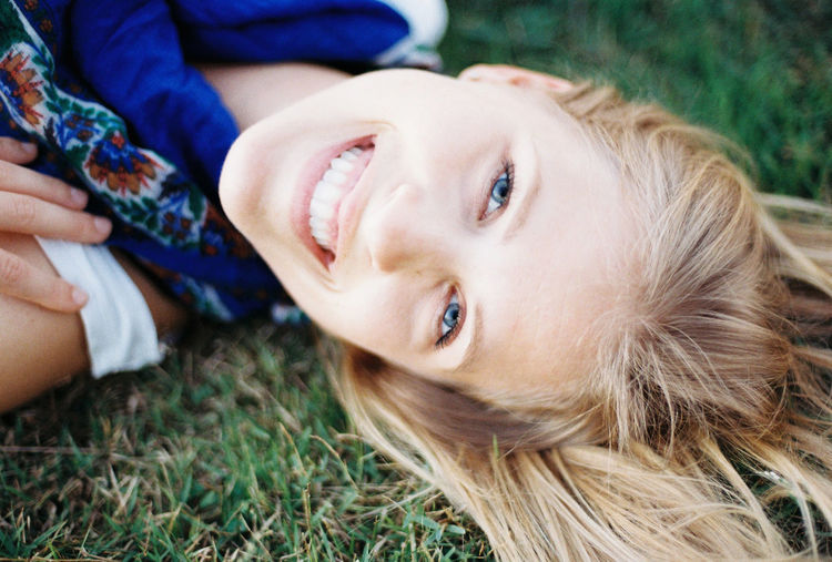 Close-up portrait of smiling girl lying on grass