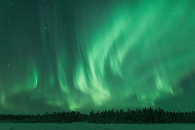 Scenic view of snow covered landscape against aurora borealis in sky at night