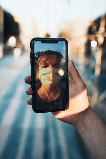 Young man having video call talking while walking downtown wearing the face mask to avoid virus