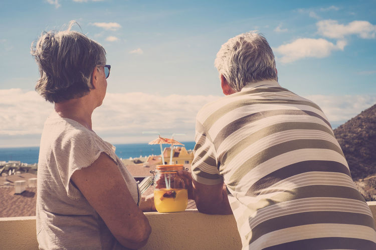 Man and woman having drink while looking at view against sky