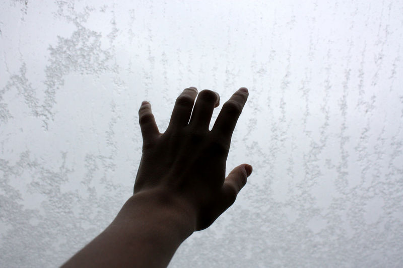 Close-up of hand touching white wall