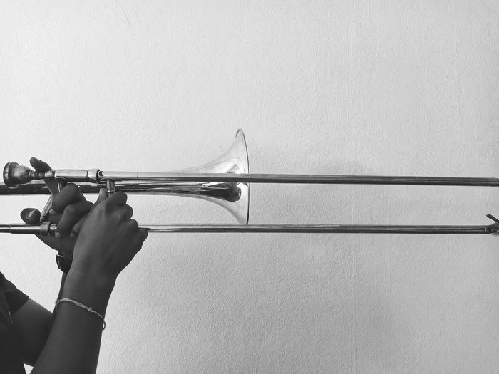 Close-up of hand holding music instrument against wall