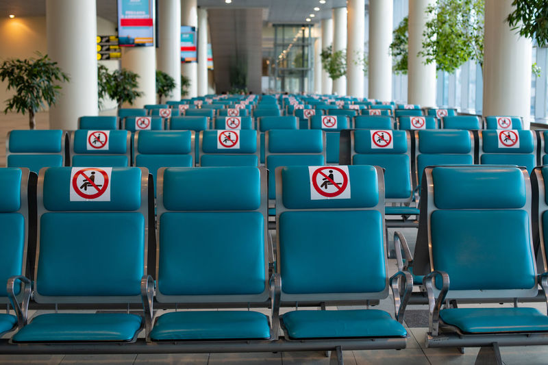 Airport during coronavirus pandemic. social distancing. empty blue chairs with a no-sitting sign