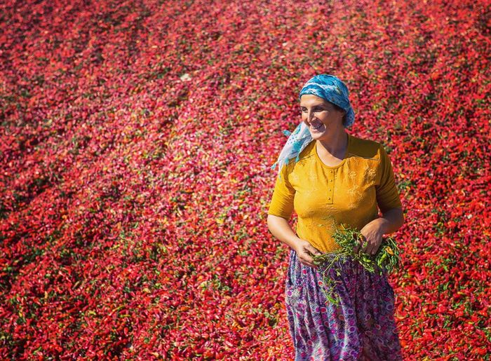 Smiling woman standing against red chili peppers
