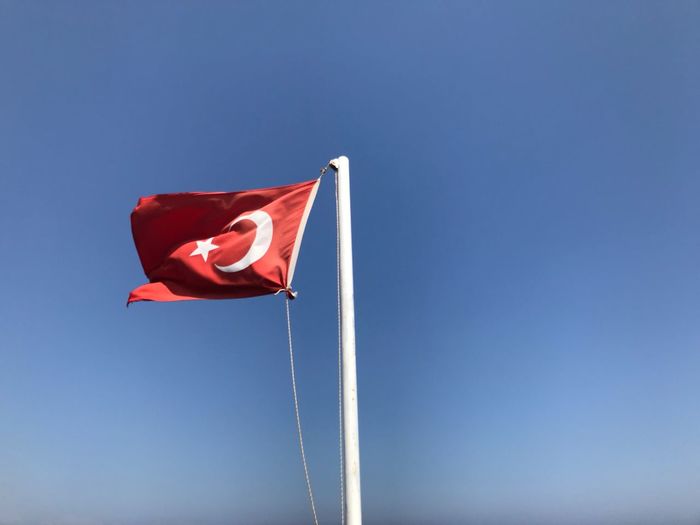 Low angle view of turkish flag against blue sky