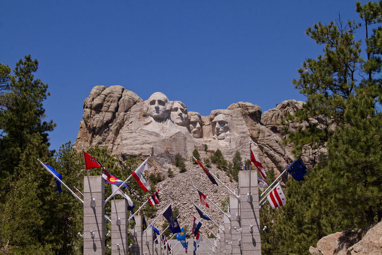Low angle view of flags at mt rushmore national monument against clear sky