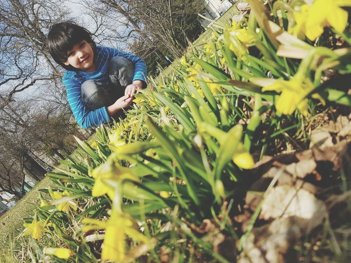 Portrait of cute boy crouching on grassy field