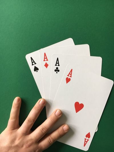 High angle view of man with three aces cards on green table