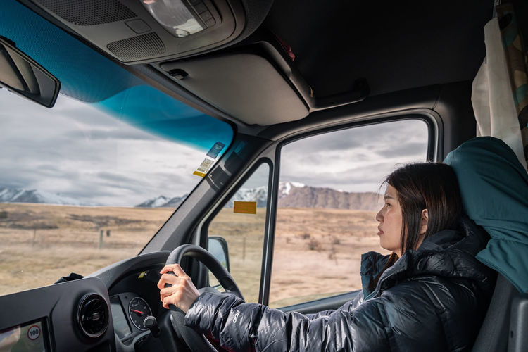 Female traveler drive camper van on empty mountainous road. new zealand road trip adventure.