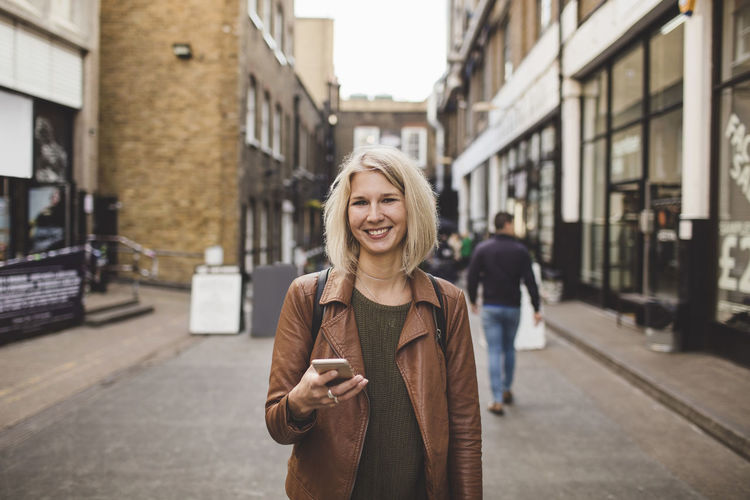 Portrait of smiling woman standing in city