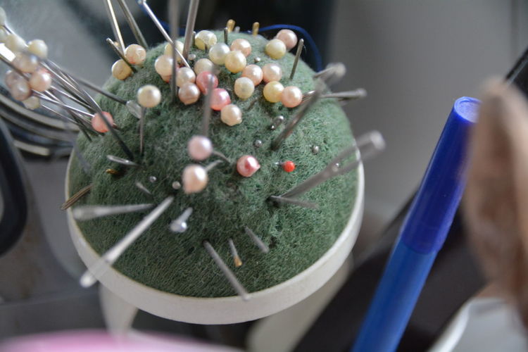 Close-up of straight pins and sewing needles on pin cushion