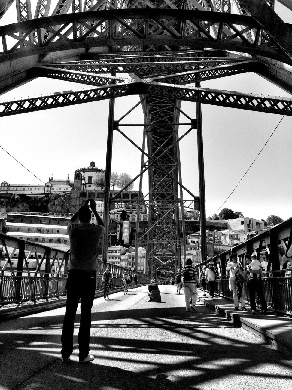 architecture, built structure, building exterior, men, lifestyles, city, person, full length, walking, leisure activity, rear view, connection, city life, street, sunlight, clear sky, bridge - man made structure, shadow