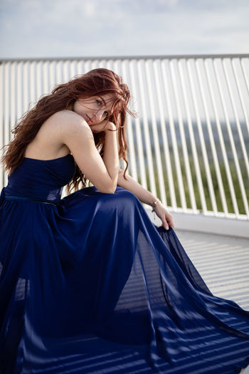Portrait of woman in dress sitting on bridge 