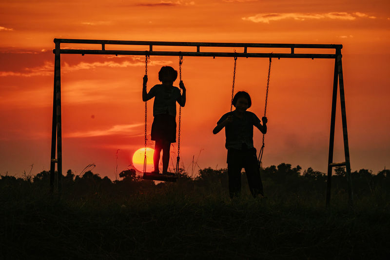 Silhouette boy swinging at playground