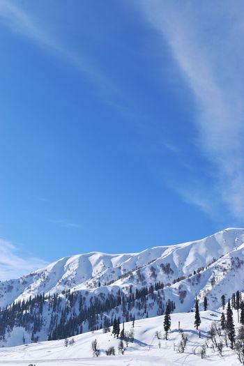 Snow covered mountains against blue sky