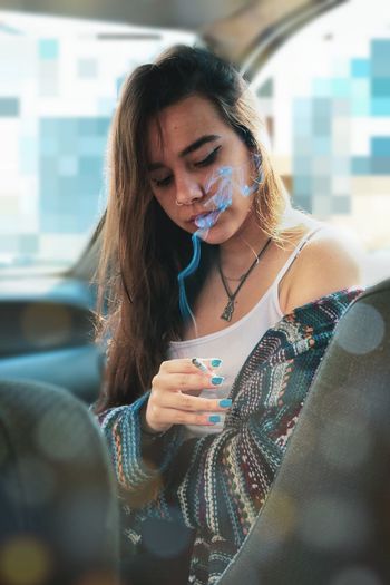 Fashionable young woman smoking cigarette while sitting in car