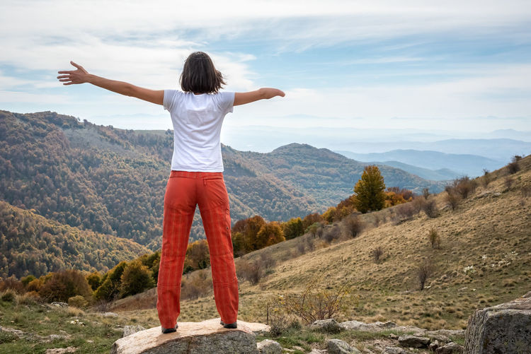 Rear view of woman standing on mountain against sky