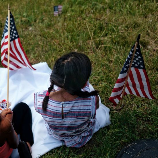 High angle view of girls sitting with american flag on field