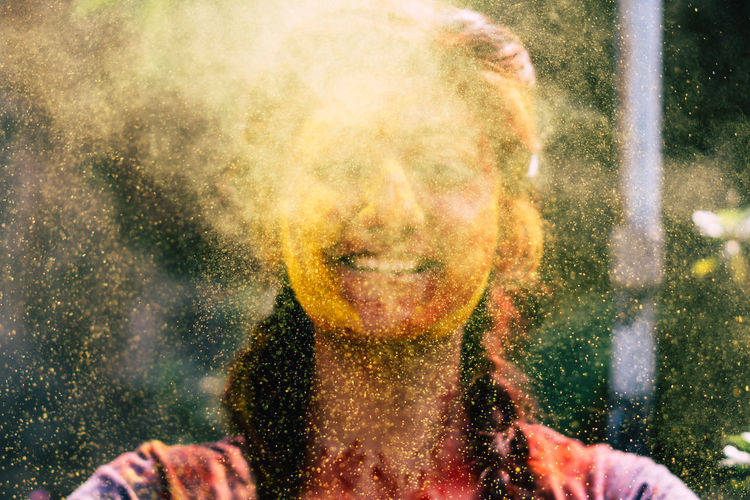 Close-up of young woman playing with powder paint during holi