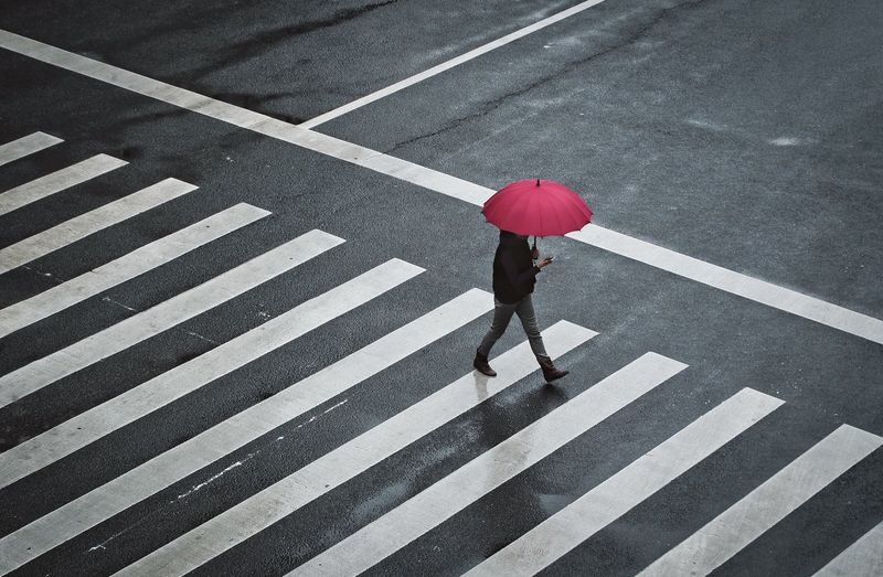 Woman walking with umbrella on road