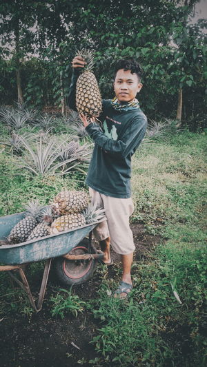 Full length of man with pineapples while standing on field