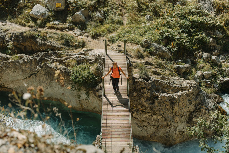 Woman walking on bridge while exploring cares trail in picos de europe national park, asturias, spain