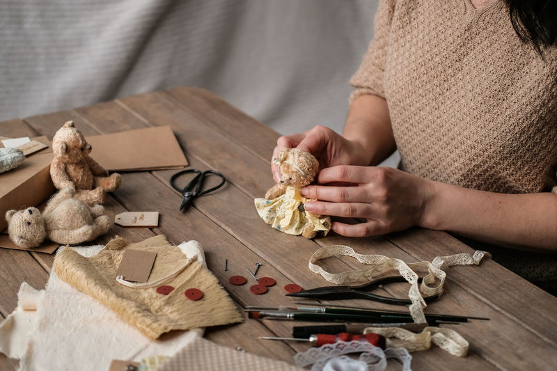 A young woman sews a teddy bear. hobby