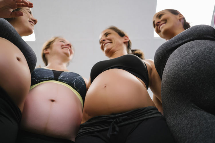 Low angle view of smiling pregnant woman standing in yoga studio