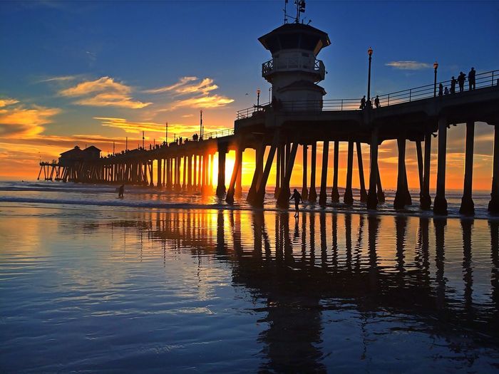 Huntington beach pier over sea against sky during sunset
