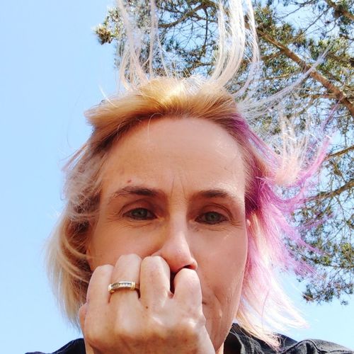 Low angle portrait of mature woman with dyed hair against tree
