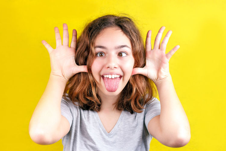 Portrait of girl teasing against yellow background