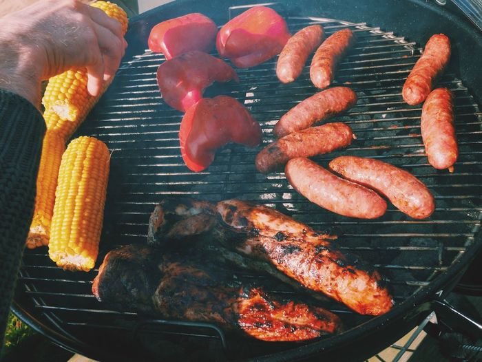 Cropped hand grilling food on barbecue