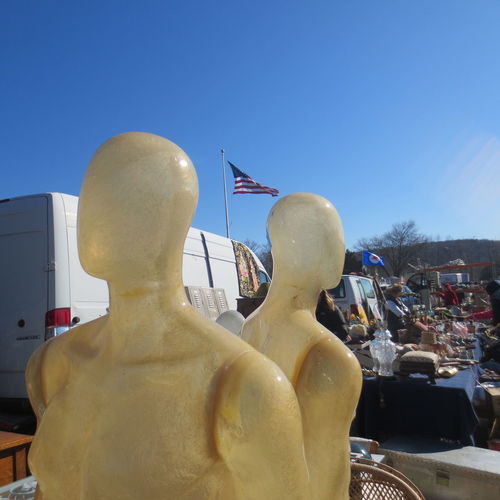 Mannequins by car against clear blue sky