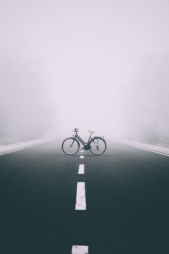 Bicycle parked on road during foggy weather