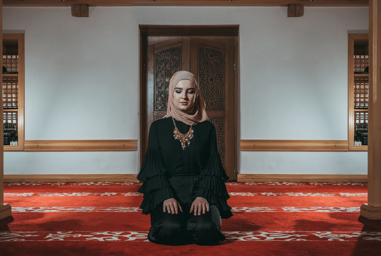 Woman in traditional clothing praying at mosque