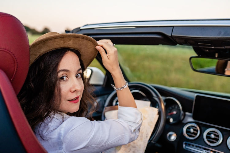 Side view of smiling woman sitting in car