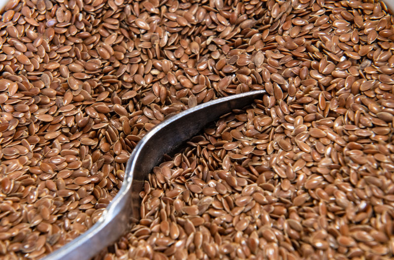 High angle view full frame of toasted brown flax seeds with metal spoon