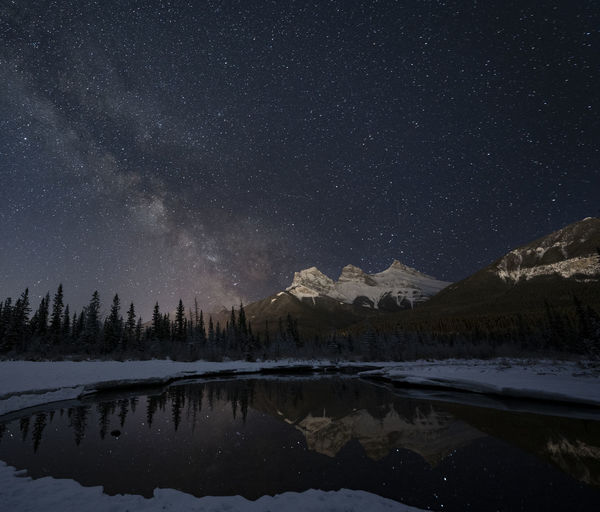 Milky way and snow capped mountains reflected in lake