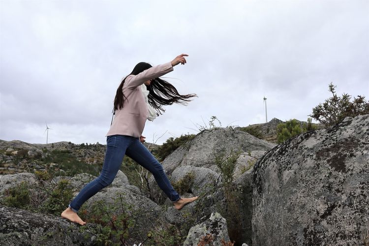 Woman running  on the rocks  against sky