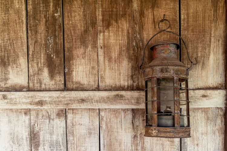 Close-up of old lamp against weathered wooden wall