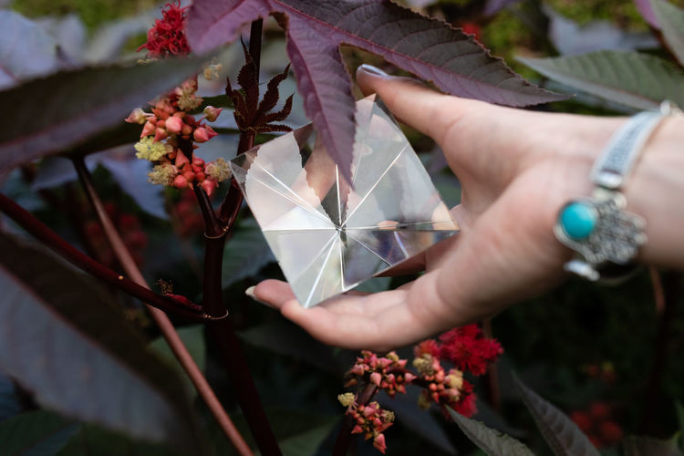 Cropped hand of woman holding pyramid crystal outdoors