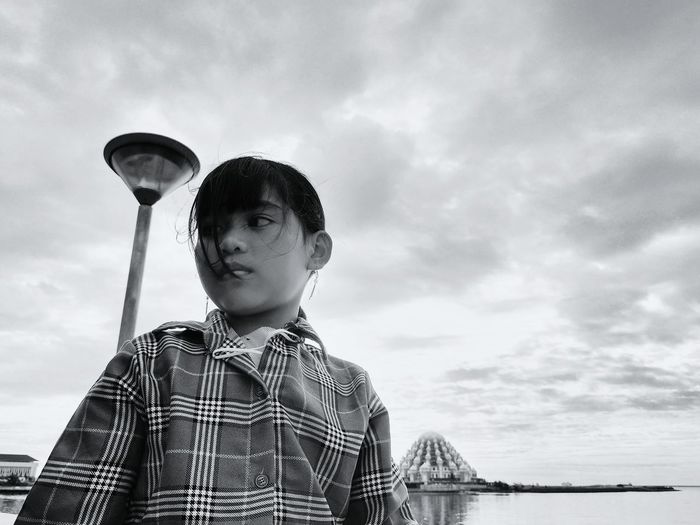 Girl looking away against sky