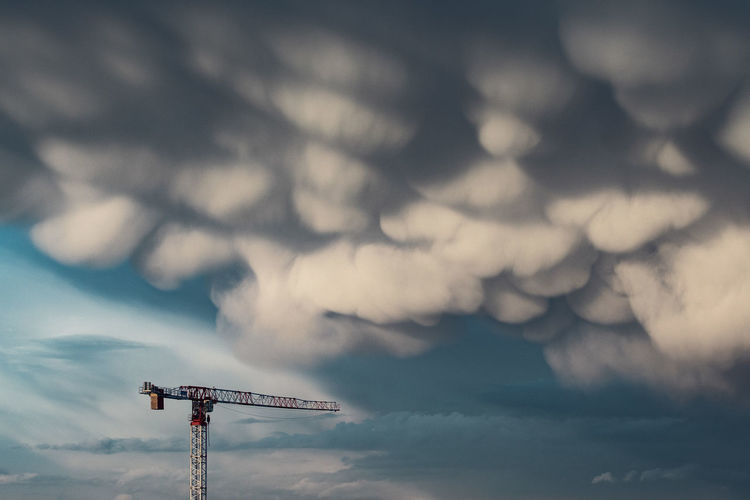 Low angle view of communications tower against cloudy sky