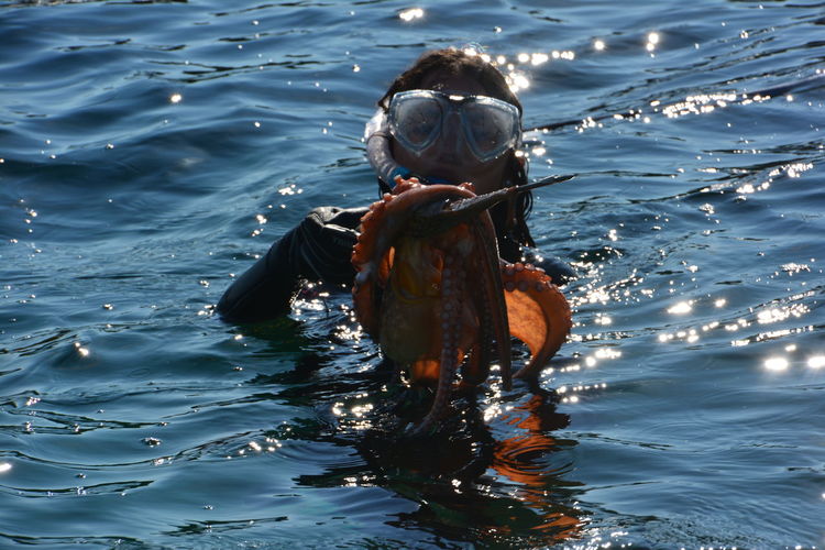 Woman fishing octopus while swimming in sea