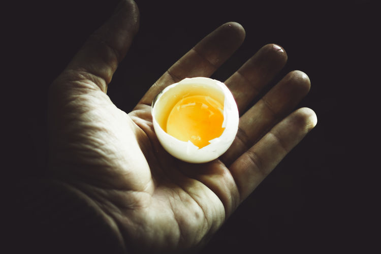 Close-up of hand holding food against black background