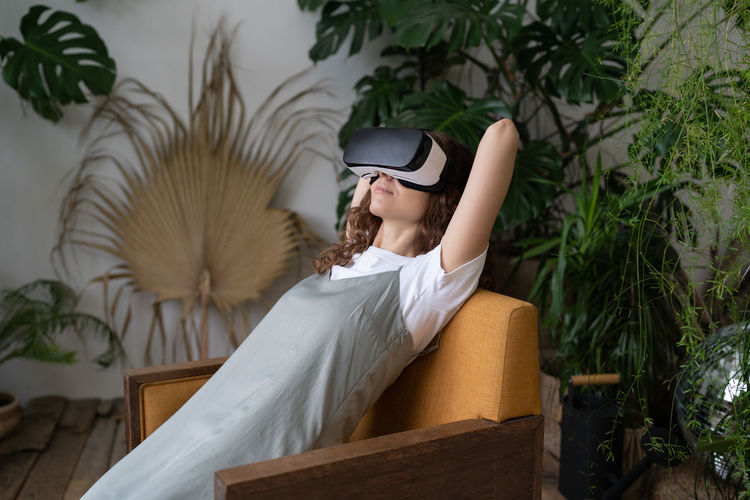 Amazed young woman using vr in home garden, resting in relaxing virtual environment. cyberspace.